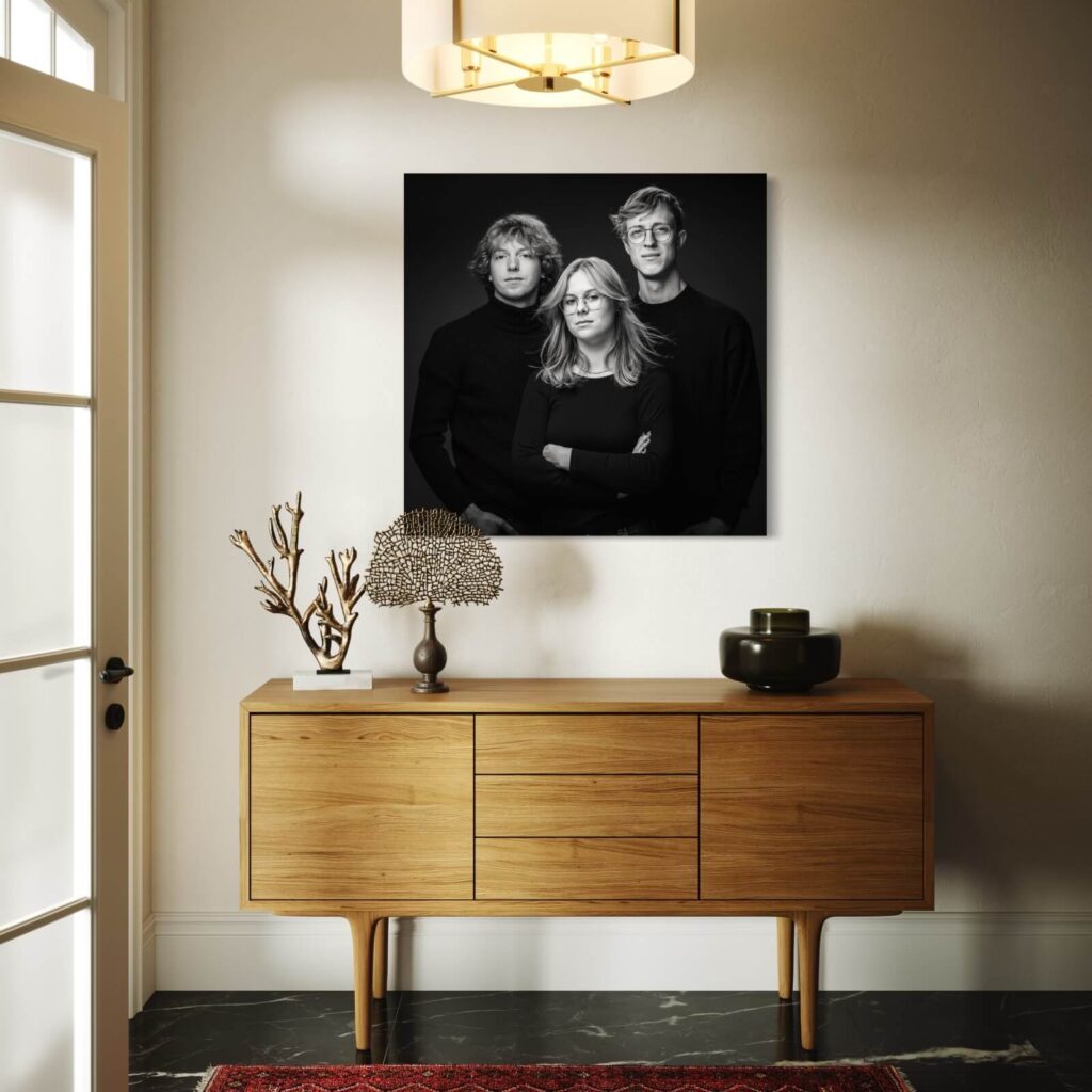 Familieportret van drie volwassen kinderen, groot aan de muur in een lichte inkomhal