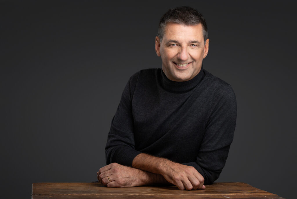 Peter Walleghem in rolkraag, handen rustig op een houten tafel